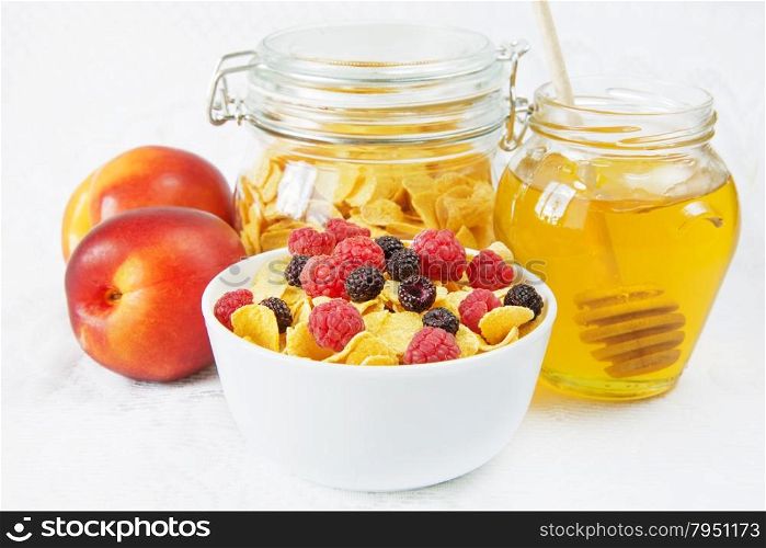 Light breakfast consisting of cornflakes with different berries and honey