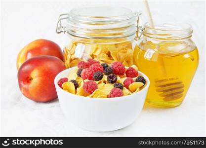 Light breakfast consisting of cornflakes with different berries and honey