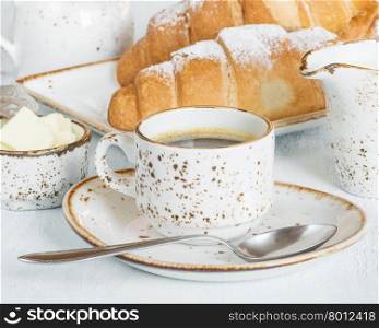 Light breakfast with a cup of coffee, croissants, cream and butter