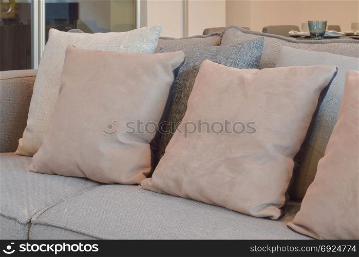 Light brown, beige and gray pillows setting on sofa in living room