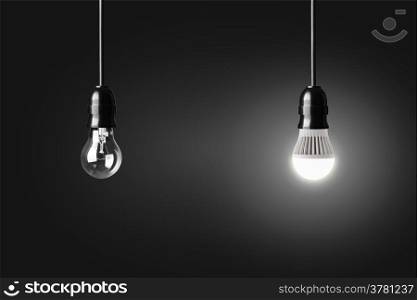 Light bulb and glowing LED bulb on black