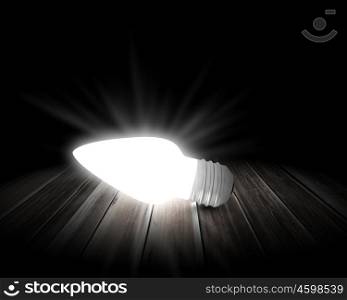 Light bulb. Background image with glowing light bulb on wooden surface