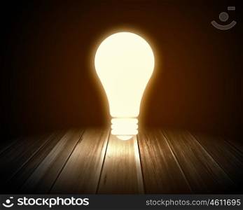 Light bulb. Conceptual image with light bulb and wooden surface