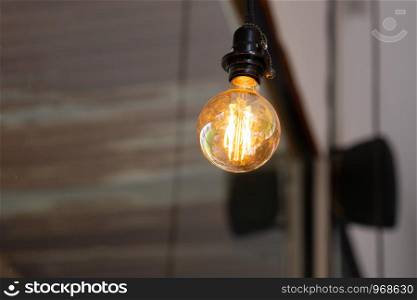 light bulb hang on ceiling with rustic wall in background