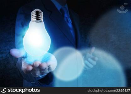 Light bulb in hand businessman on blue tone as concept