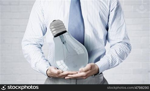 Light bulb in hand. Close up of businessman holding in hands glowing light bulb