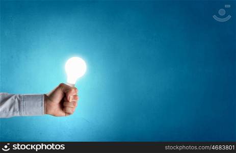 Light bulb in hand. Close up of hand holding glowing light bulb