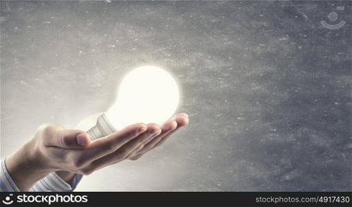 Light bulb in hand. Close up of hand holding glowing light bulb