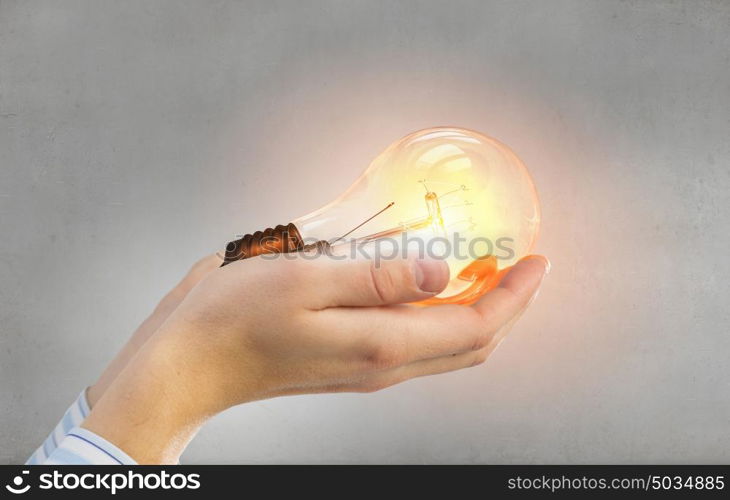 Light bulb in hand. Close up of hand holding glowing light bulb