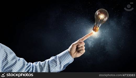 Light bulb in hand. Close up of hand pointing with finger at light bulb