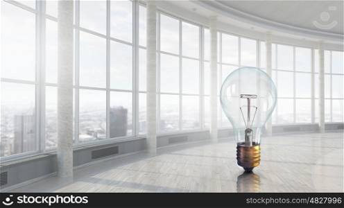 Light bulb in modern office. Glass light bulb against office room with large window