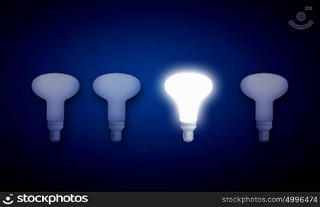 Light bulb. Light bulbs on dark background with one burning