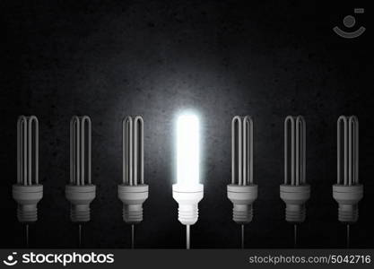 Light bulb. Light bulbs on dark background with one glowing