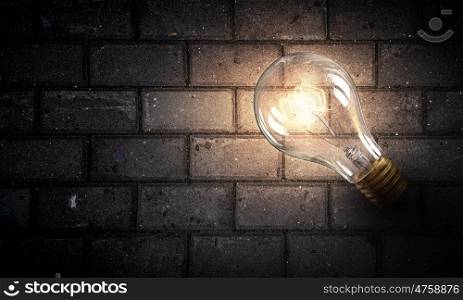 Light bulb on brick surface. Power and energy concept with glass light bulb on brick wall