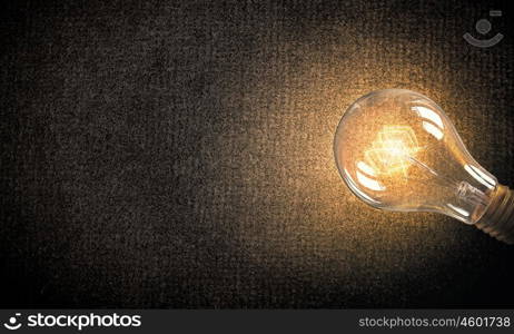 Light bulb on material surface. Power and energy concept with glass glowing light bulb o backdrop