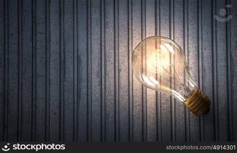 Light bulb on metal surface. Power and energy concept with glass glowing light bulb o backdrop