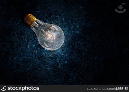 Light bulb on soil. Glowing glass light bulb on soil background