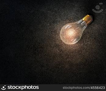 Light bulb on stone surface. Glass glowing light bulb on stone background