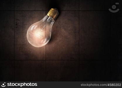 Light bulb on stone surface. Glass glowing light bulb on stone background