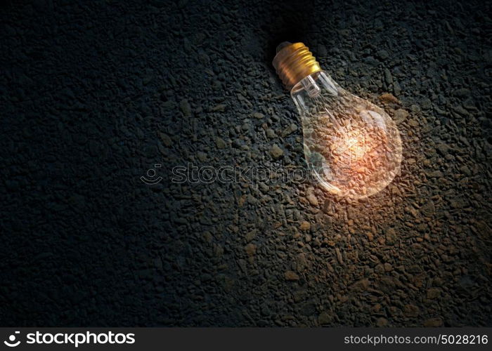 Light bulb on stone surface. Glass glowing light bulb on stone background