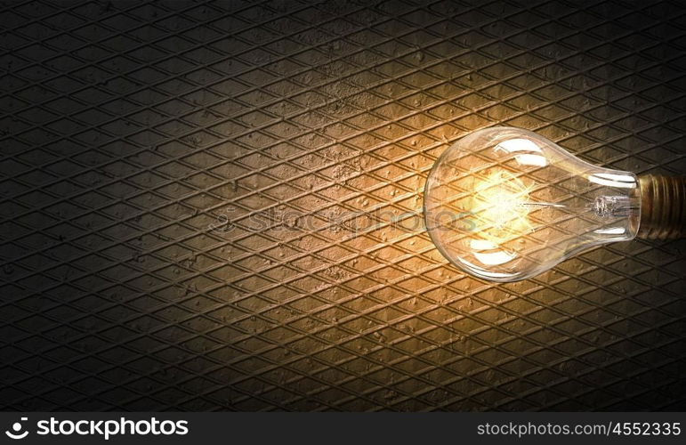 Light bulb on stone surface. Power and energy concept with glass glowing light bulb on concrete backdrop