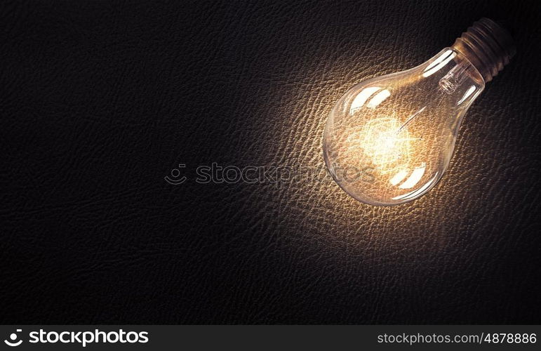 Light bulb on stone surface. Power and energy concept with glass glowing light bulb on concrete backdrop