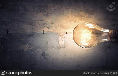Light bulb on stone surface. Power and energy concept with glass glowing light bulb on concrete backdrop