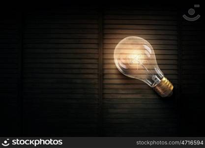 Light bulb on wooden surface. Glowing glass light bulb on wooden table