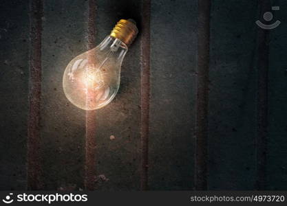 Light bulb on wooden surface. Glowing glass light bulb on wooden table