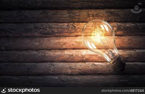 Light bulb on wooden surface. Power and energy concept with light bulb on wooden surface