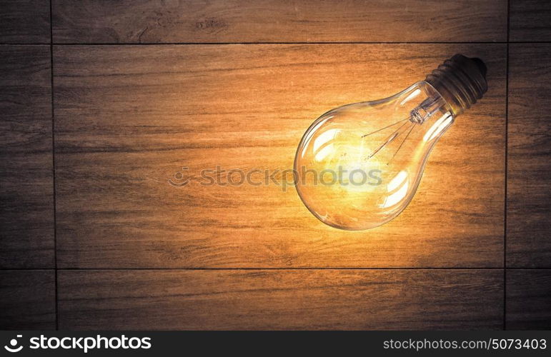 Light bulb on wooden surface. Power and energy concept with light bulb on wooden surface