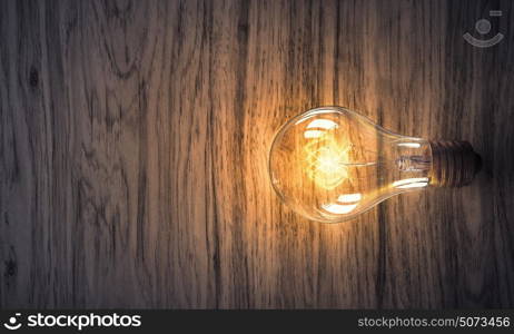 Light bulb on wooden surface. Power and energy concept with light bulb on wooden surface