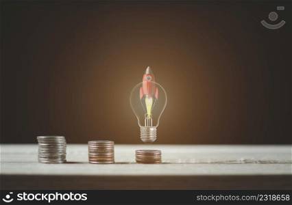 Light bulb rocket with coin ladder for financial plans or business ideas.