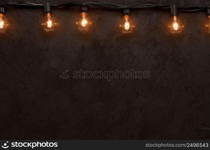 Light bulb string light on dark background top border with copy-space