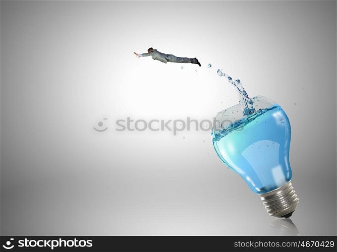 Light bulb with clear water. Conceptual image with light bulb filled with clear water and businessman inside