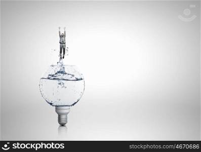 Light bulb with clear water. Conceptual image with light bulb filled with clear water and businessman inside