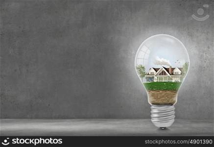 Light bulb with concept of ecological construction in it. Green light bulb