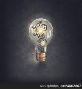 Light bulb with gears. Light bulb concept with gears inside on cement background