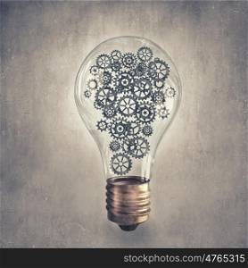 Light bulb with gears. Light bulb concept with gears inside on cement background