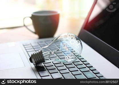 light bulb with illustration gear flare on laptop with blur background , idea working concept