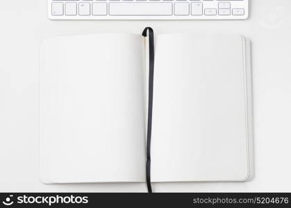 Light clean workplace. White workplace with keyboard and notebook, view from above