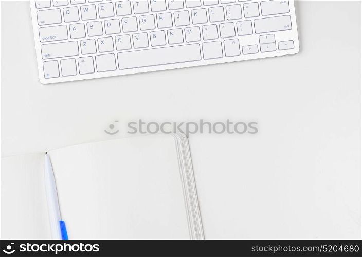 Light clean workplace. White workplace with keyboard and notebook, view from above