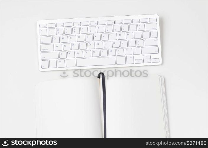 Light clean workplace. White workplace with keyboard and notebook, view from above