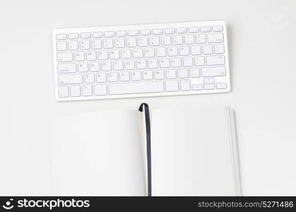 Light clean workplace. White workplace with keyboard and notebook, view from above