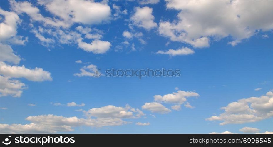Light cumulus clouds in the blue sky. A bright sunny day. Wide photo.