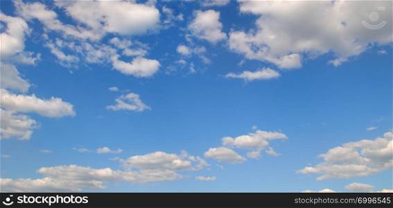 Light cumulus clouds in the blue sky. A bright sunny day. Wide photo.