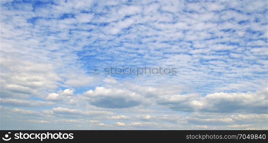 Light cumulus clouds in the blue sky. Wide image.