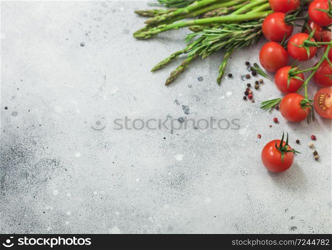 Light food background with asparagus, cherry tomatoes and rosemary on light background. Space for text