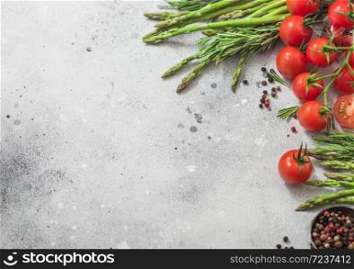 Light food background with healthy cherry tomatoes, asparagus and rosemary on with bowl of pepper. Space for text
