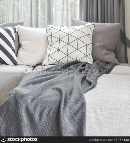 Light gray L shape sofa with varies pattern and white pillows in modern living corner